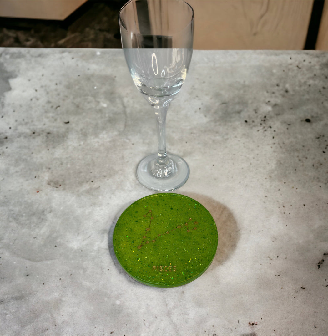 Green Pisces zodiac coaster with wine glass on table.