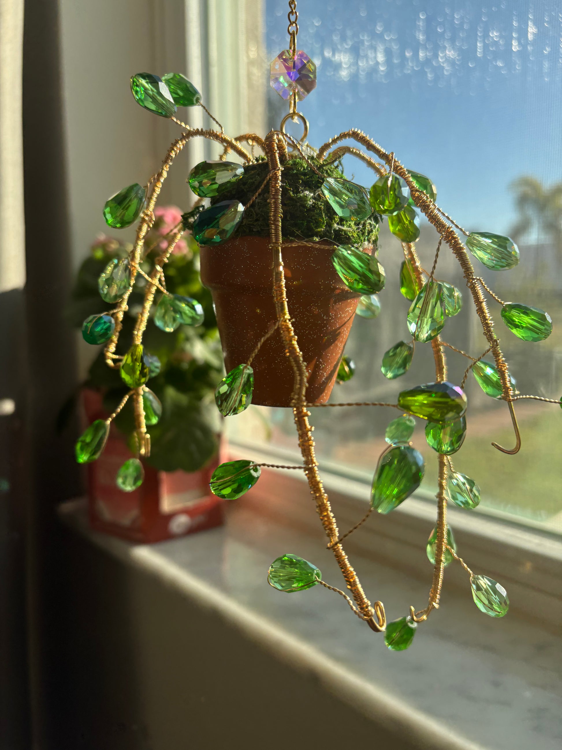 String of Pearls Sun Catcher with green crystal beads and gold wire in a mini terracotta pot, hanging near a sunny window for boho home decor.